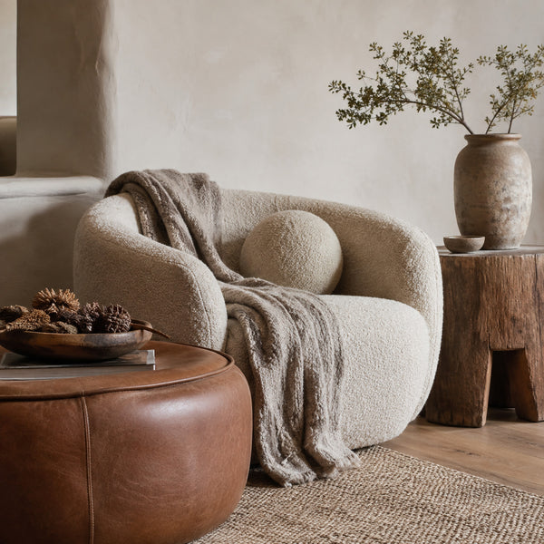 Bouclé armchair with leather ottoman, woven blanket and raw wood side table